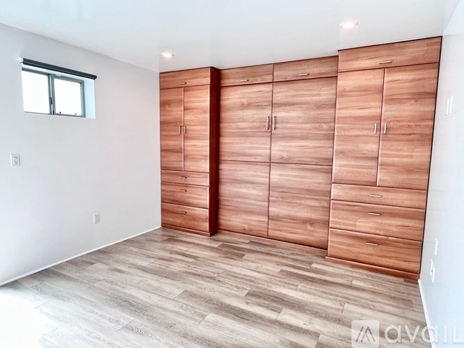 A room with a window and a set of wooden cabinets.