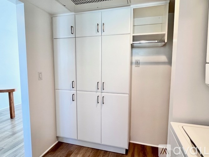 A white kitchen pantry with a white fridge and white cupboards.