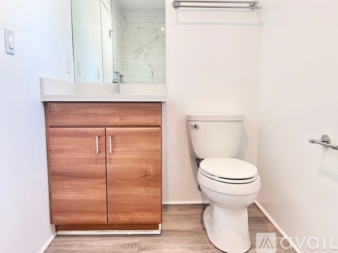 A white toilet sits next to a wooden cabinet in a bathroom.
