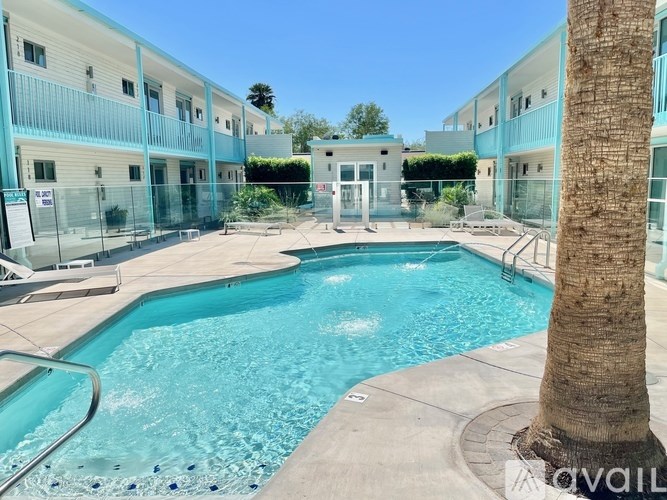 A pool surrounded by apartment buildings and a palm tree.
