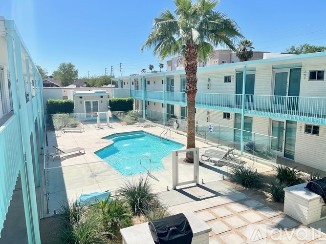 A pool surrounded by a balcony and palm trees.