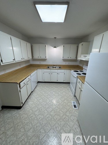 A kitchen with white cabinets and a wooden countertop.