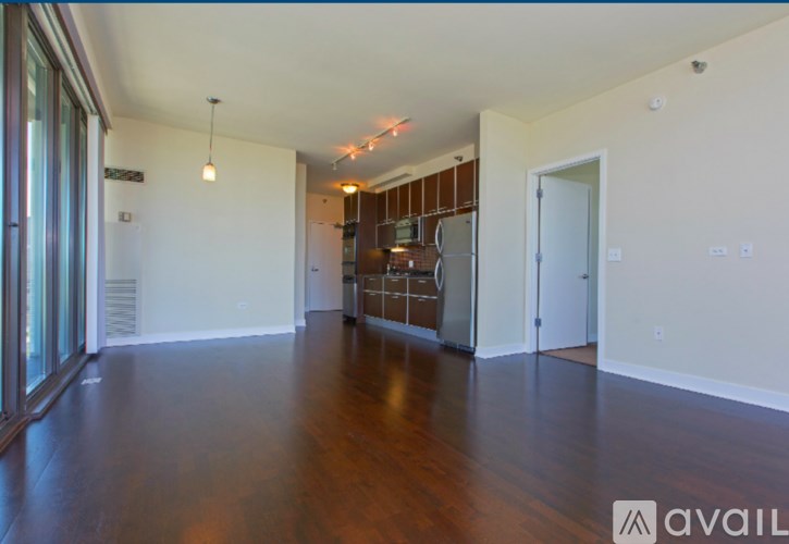 A spacious living room with hardwood floors and a kitchen in the background.