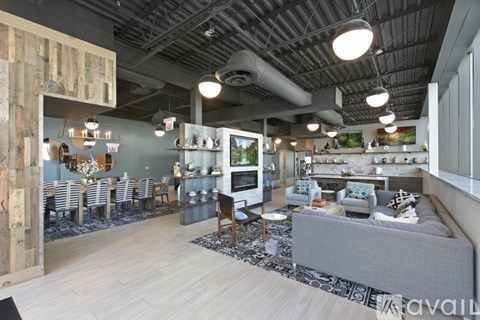 A modern living room with a grey sofa and a dining area with chairs.