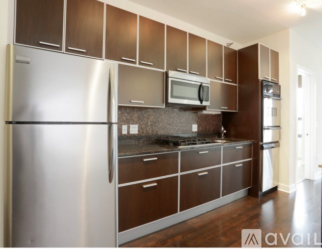 A kitchen with brown cabinets and a stainless steel refrigerator.
