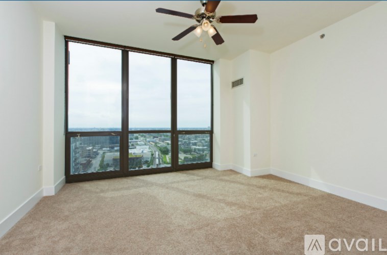 A room with a ceiling fan and large windows overlooking a cityscape.