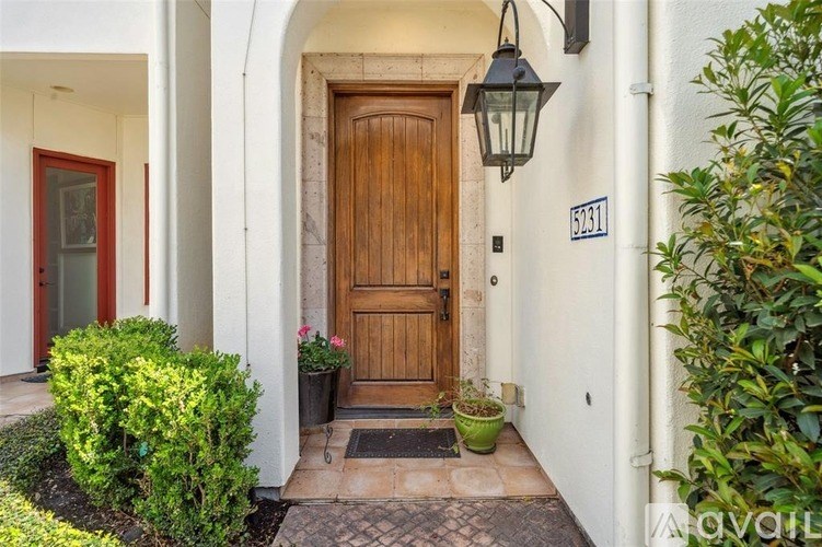 A wooden door is at the end of a hallway with a black lantern hanging above it.