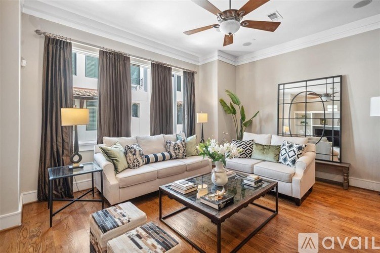 A living room with a white couch, a glass coffee table, and a ceiling fan.