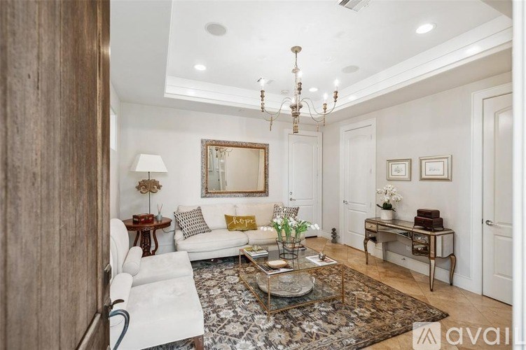 A living room with a white couch, a coffee table, and a chandelier.