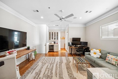 A living room with a grey couch and a white ceiling fan.