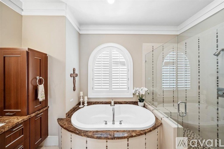 A bathroom with a large tub and a window with shutters.