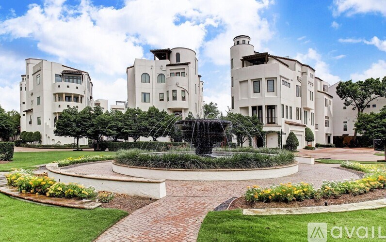 A large white building with a circular garden in front.