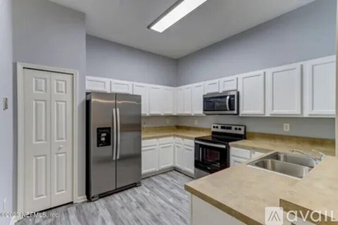 A kitchen with white cabinets and a stainless steel refrigerator.