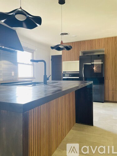 A modern kitchen with a dark countertop and wooden cabinets.