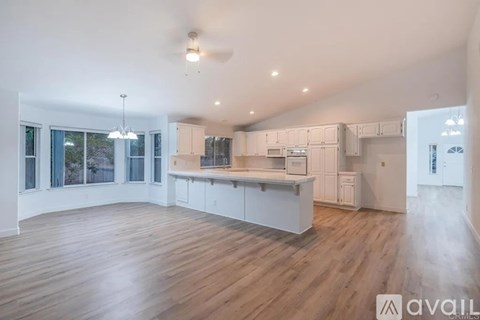 A spacious kitchen with white cabinets and a wooden floor.