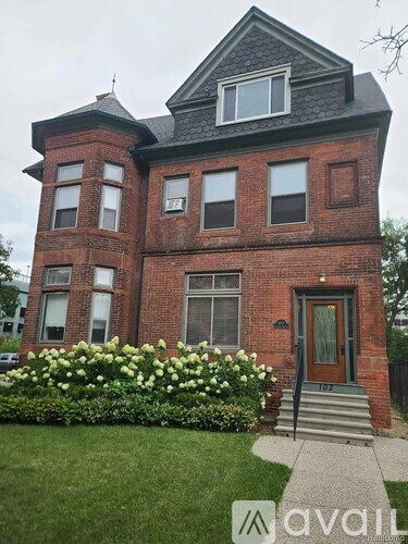 A red brick house with a green lawn in front.