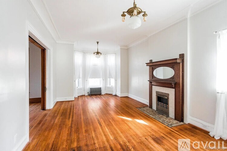 A large, empty room with wood floors and a fireplace.