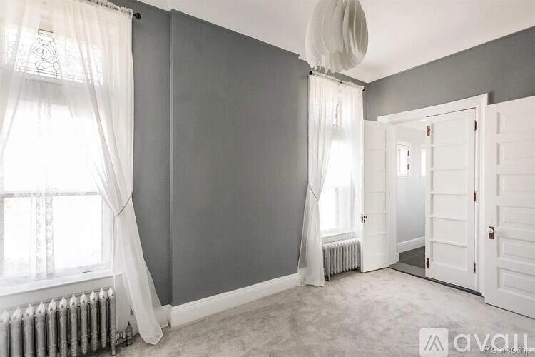 A room with grey walls and a window with white curtains.