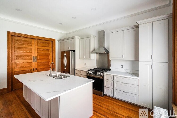 A kitchen with white countertops and wooden floors.