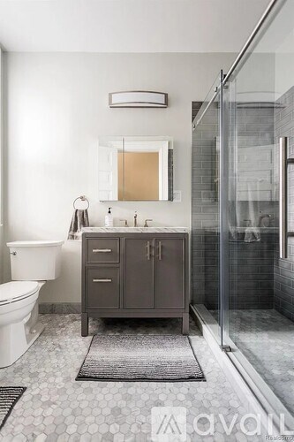 A bathroom with a white toilet, a sink with a cabinet, and a glass shower stall.