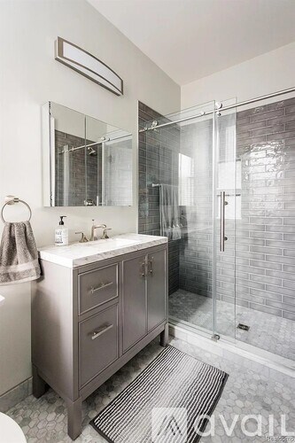 A bathroom with a white sink and a glass shower stall.