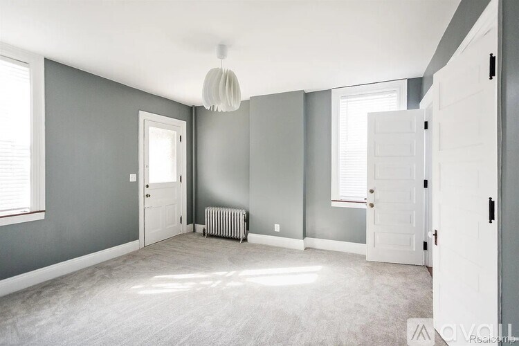 A room with grey walls and a white ceiling with a radiator and a window.