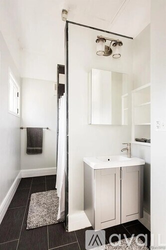 A white sink is in a white cabinet under a mirror in a white bathroom.