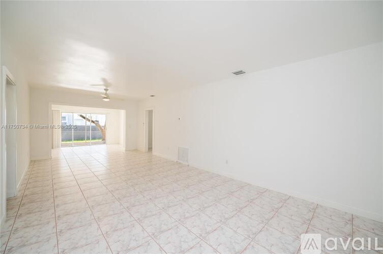 A spacious empty room with tiled flooring and white walls.