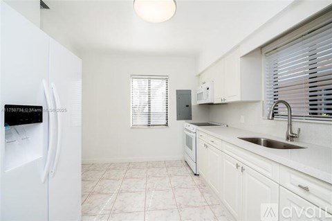 A kitchen with white cabinets and a white fridge.