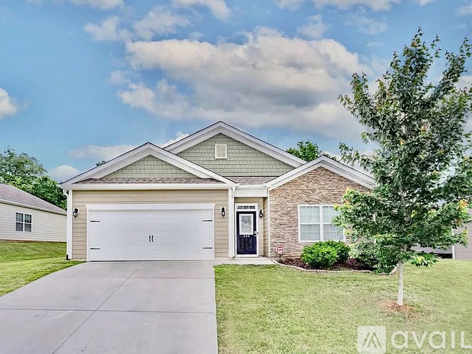 A house with a garage and a tree in front.