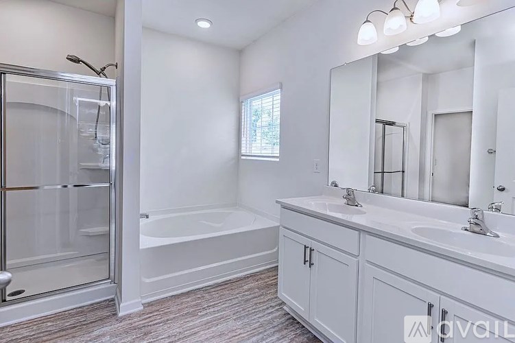 A white bathroom with a walk-in shower and double sinks.
