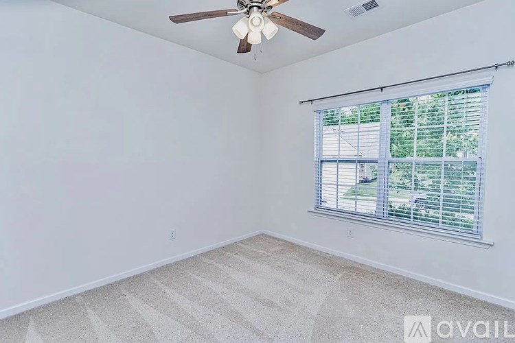 A room with a ceiling fan and a window with blinds.