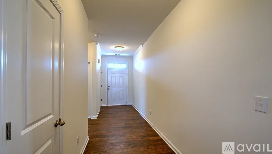 A long hallway with white walls and wood floors.