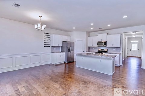A kitchen with white cabinets and a wooden floor.