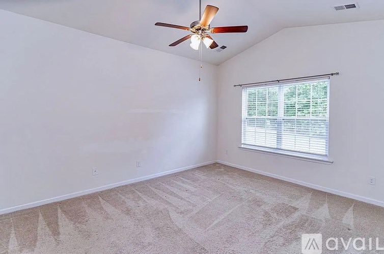 A room with a ceiling fan and a window with blinds.