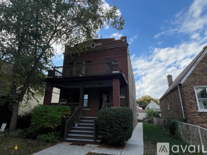 A house with a brick facade and a porch with stairs leading up to it.