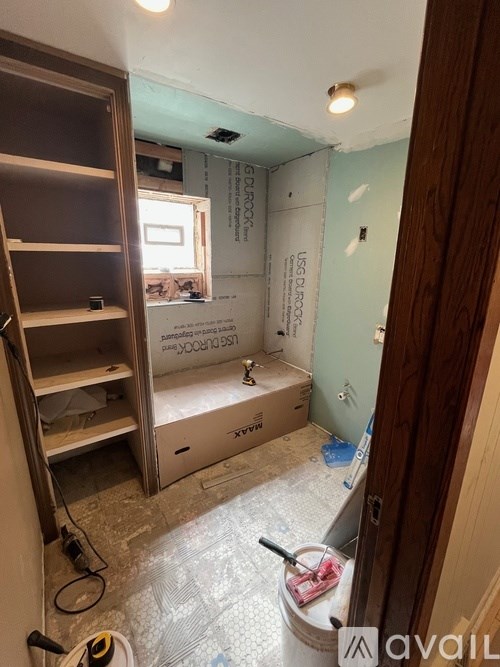 A room under construction with a ladder and a bucket of paint.