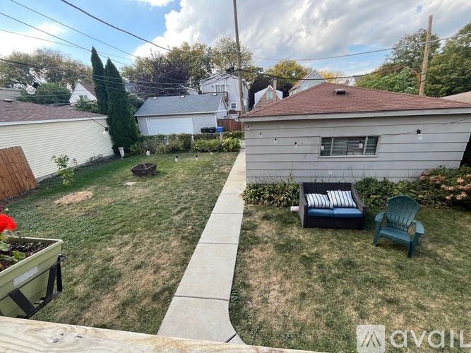 A backyard with a lawn, a chair, and a planter box.