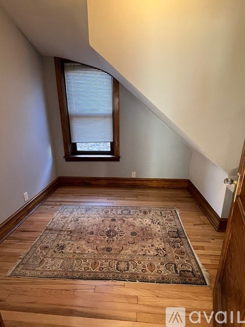 A room with a rug on the floor and a window with blinds.
