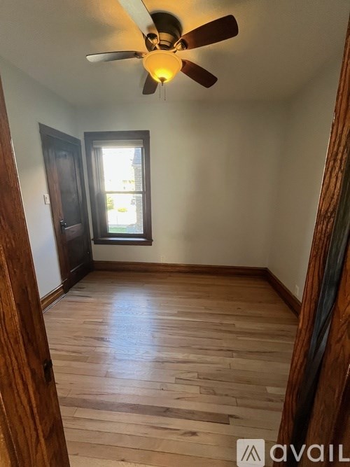 A room with a ceiling fan and wooden flooring.