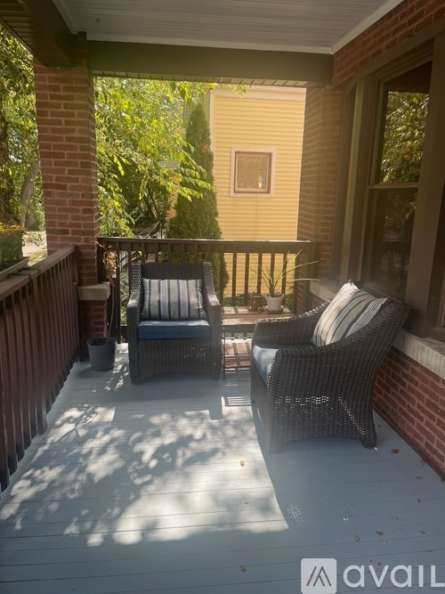 A patio with a wicker chair and a cushion is on the balcony.