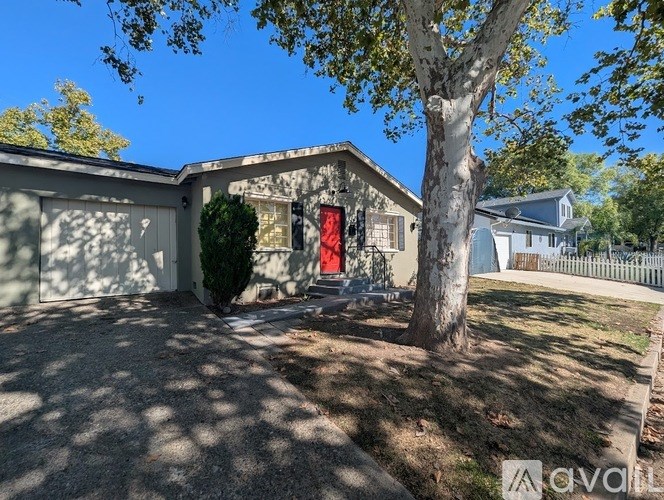 A house with a red door is surrounded by a white fence.
