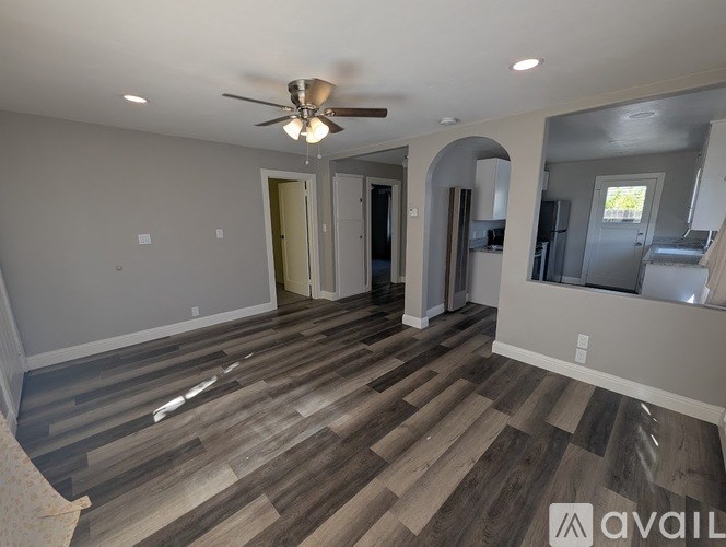 A spacious room with a ceiling fan and wooden flooring.