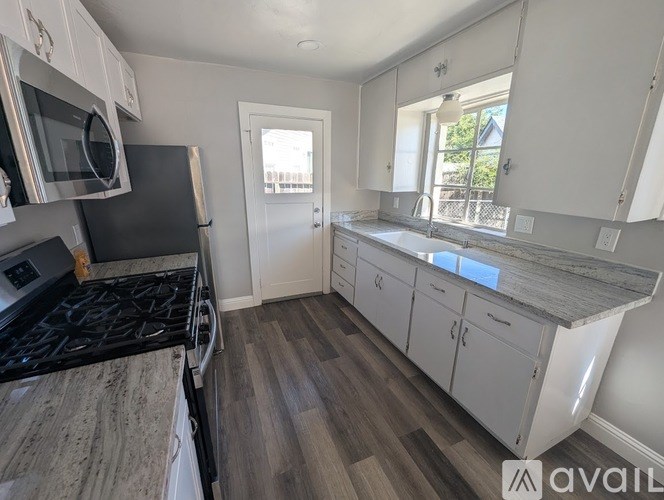 A kitchen with a black stove top oven and white cabinets.