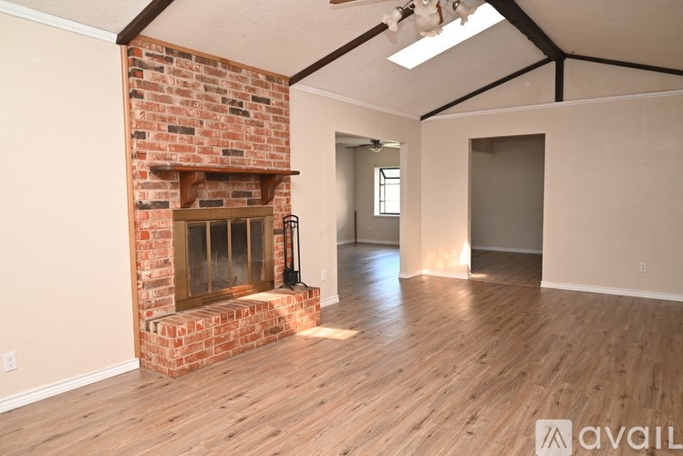 A room with a brick fireplace and wooden floors.