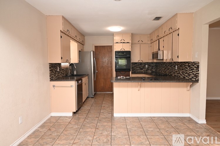 A kitchen with beige cabinets and a black countertop.