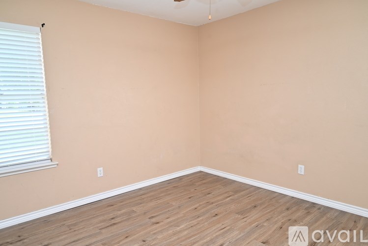 A room with wooden flooring and a window with blinds.