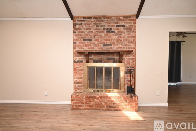 A room with a brick fireplace and wooden floors.