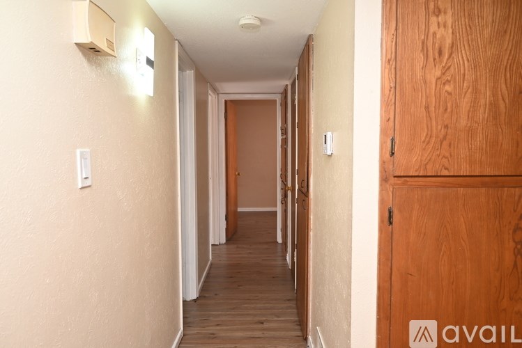 A long hallway with a door at the end and a wooden door on the right.