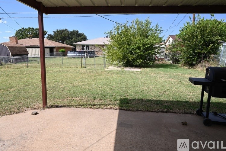 A backyard with a patio and a BBQ grill.